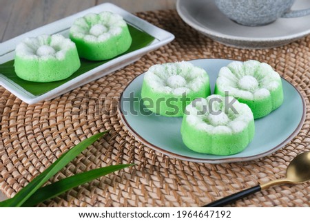 Indonesian Traditional steamed cake Kue Putu Ayu, made from rice flour, 
grated coconut, pandanus and suji leaves, served in plate on wooden table.