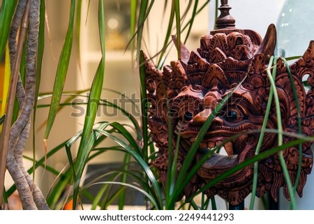Indonesian wooden mask behind plants