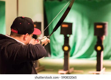 Indoor Archery Range, Single Man Aiming Drawn Bow With Arrow Towards Targets