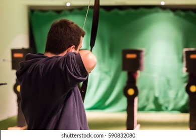 Indoor Archery Range, Single Man Aiming Drawn Bow With Arrow Towards Targets