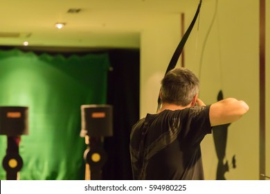 Indoor Archery Range, Single Man Aiming Drawn Bow With Arrow Towards Targets