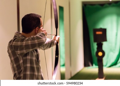 Indoor Archery Range, Single Man Aiming Drawn Bow With Arrow Towards Targets