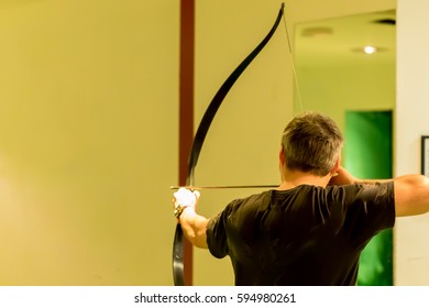 Indoor Archery Range, Single Man Aiming Drawn Bow With Copy Space