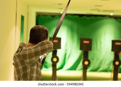 Indoor Archery Range, Single Man Aiming Drawn Bow With Arrow Towards Targets