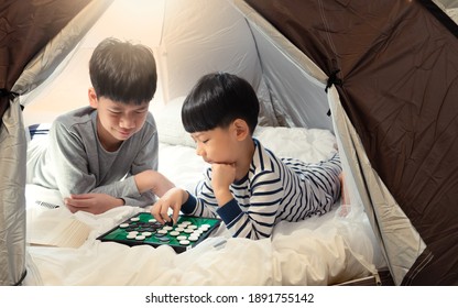 Indoor Camping Tent - Stay At Home Activity For Family During Covid 19 Pandemic Lockdown Concept. Young Asian Brothers Kids Playing Games Together In A Teepee In Living Room. Happy, Siblings, April 10