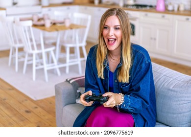 Indoor Cozy Image Of Stylish Woman Sitting On Sofa At Her Living Room. Playing Video Game, Exited Face.