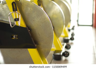 Indoor Cycling Spin Bike Wheel Yellow Steel Frame In Row Close Up High Light Window Background