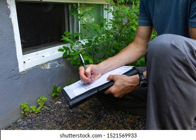 Indoor damp & air quality (IAQ) testing. A close up view of a building inspector checking exterior walls and windows of a domestic dwelling, using a pen and paper to fill regulation paperwork. - Shutterstock ID 1521569933