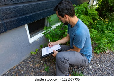 Indoor Damp & Air Quality (IAQ) Testing. A Close Up View On Environmental Home Quality Inspector At Work, Filling In A Form As He Inspects The Exterior Of A Cellar Window, With Room For Copy.