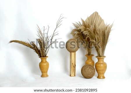 The indoor decorations consist of dry palm leaves, dry weeds and dry twigs in jars, large rattan balls and wooden poles.