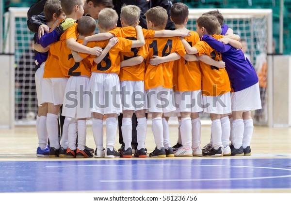 Indoor football soccer match for children.\
Coach giving young soccer futsal team advices. Youth soccer team\
before final game. Football match for children. Coach briefing.\
Soccer football\
background.