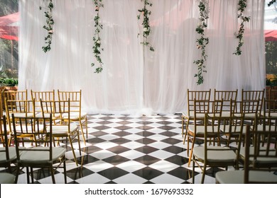 Indoor garden wedding setup with golden Tiffany chairs with a big white clothes backdrop
