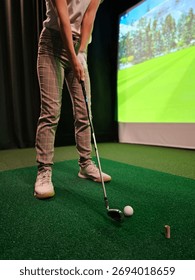 Indoor golfing practice session with a virtual simulator on a green turf surface