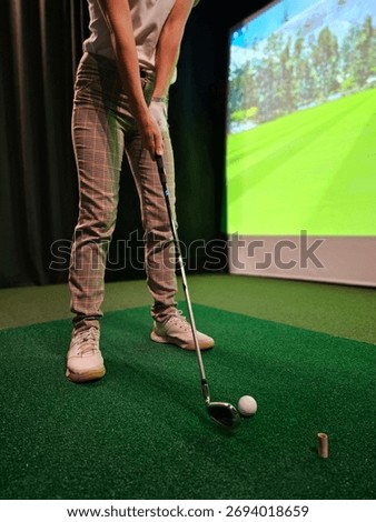 Indoor golfing practice session with a virtual simulator on a green turf surface