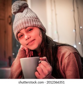 Indoor Image Of An Asian, Indian Beautiful, Serene Young Woman Looking Away And Contemplating While Drinking And Holding A Cup Of Coffee In Winter Season At Home. She Is Wearing Warm Clothes.