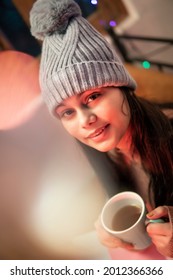 Indoor Image Of An Asian, Indian Beautiful, Serene Young Woman Looking Away And Contemplating While Drinking And Holding A Cup Of Coffee In Winter Season At Home. She Is Wearing Warm Clothes.