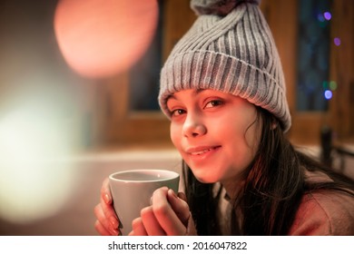 Indoor Image Of An Asian, Indian Beautiful, Serene Young Woman Looking Away And Contemplating While Drinking And Holding A Cup Of Coffee In Winter Season At Home. She Is Wearing Warm Clothes.