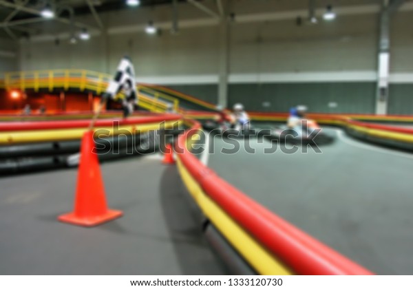 Indoor kart racing on the go kart track. Blurred\
background image.