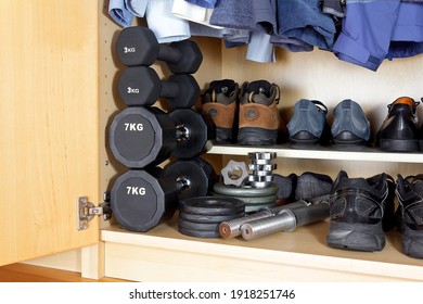 Indoor And Oudoor Sports Equipment For The Covid Pandemic: Weights, Dumbbells, Running Shoes And Hiking Boots At The Bottom Of A Wardrobe