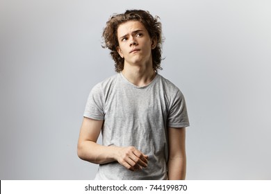 Indoor Picture Of Attractive Thoughtful Young Clean Shaven Male With Wavy Hairstyle Looking Up Having Pensive Pondering Expression, Weighing Pros And Cons Of Some Decision, Idea, Offer Or Proposal