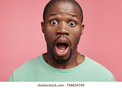 Indoor Picture Of Scared Bugged Eyed African American Male Looks With Bated Breath, Horrified To Hear Shocking News From Relatives, Finds Out About Serious Disease Of His Mother. Surprisment Concept