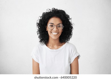 Indoor portrait of beautiful brunette young dark-skinned woman with shaggy hairstyle smiling cheerfully, showing her white teeth to camera while feeling happy and carefree on her first day-off - Shutterstock ID 640005220