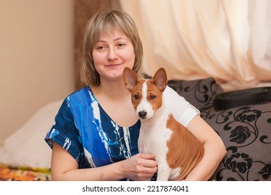 Indoor Portrait Of Beautiful Mature Woman With Basenji Puppy