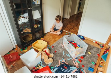 Indoor portrait of a child playing in a very messy room, throwing teddy bear on the floor
