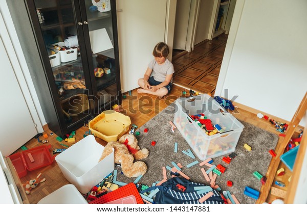 とても汚い部屋で遊ぶ子供の室内のポートレート 床にテディベアを投げる の写真素材 今すぐ編集