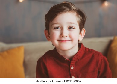 indoor portrait of happy handsome stylish child boy sitting on cozy couch in casual clothing