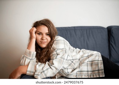 Indoor portrait of lazy bored carefree smiling relaxed caucasian plus size female lying on couch leaning head on hand with apathy and looking at camera, enjoying stress free weekend - Powered by Shutterstock