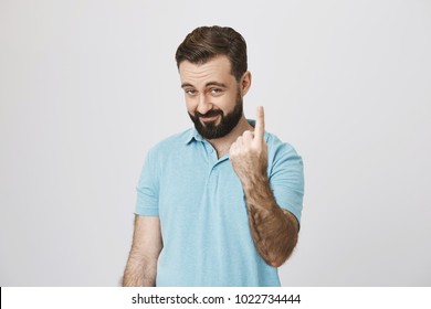 Indoor Portrait Of Playful Bearded Adult Showing Come Here Gesture With Index Finger And Smiling Over Gray Background. You Tell Me That You Drank Only One Bottle Of Beer, Come On