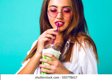 Indoor portrait of pretty cute hipster woman drinking tasty green milk shake, mint background, hippie style, vintage pastel sweet colors. retro sunglasses, makeup, trendy clothes, studio fashion. - Powered by Shutterstock