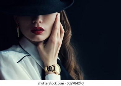 Indoor portrait of a young beautiful  fashionable woman wearing stylish accessories. Hidden eyes with hat. Female fashion, beauty and advertisement concept. Close up. Copy space for text