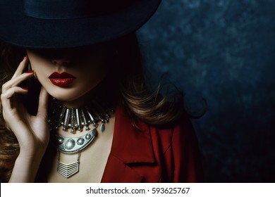  Indoor portrait of a young beautiful  fashionable woman wearing stylish accessories. Hidden eyes with hat. Female fashion, beauty and advertisement concept. Close up. Copy space for text