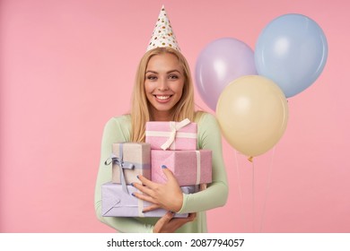 Indoor Portrait Of Young Blonde Female, Wears Green Dress, Party Hat Posing Over Pink Background