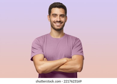 Indoor portrait of young european caucasian man isolated on purple background, standing in purple t-shirt with crossed arms, smiling and looking straight at camera - Powered by Shutterstock