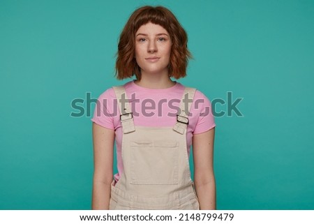 indoor portrait of young ginger female posing over blue background starring into camera with serious emotionless facial expression Stock photo © 