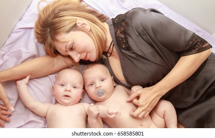 Indoor Portrait Of Young Happy Smiling Mother With Her Twin Babies At Home