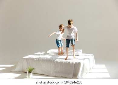 Indoor positive activity. Small children jumping on a bed and having fun in sunshine - Powered by Shutterstock