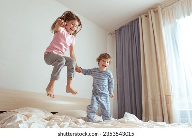 Indoor positive activity. Small children jumping on a bed and having fun - Powered by Shutterstock