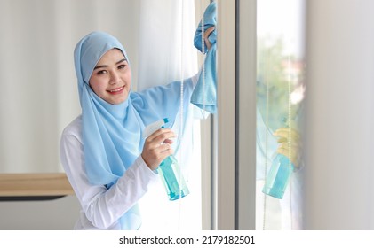 Indoor Shot Active Young Beautiful Asian Housewife Woman Holding Cleaning Spray, Washing Window Glass. Portrait Cute Girl With Happy Emotional Cleaning Bedroom In New Apartment After Moved In. 