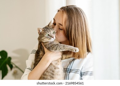 Indoor shot of amazing lady holding pet. Portrait of young woman holding cute striped cat with green eyes. Female hugging her cute kitty. Adorable domestic pet concept. Indoor shot of amazing lady - Powered by Shutterstock