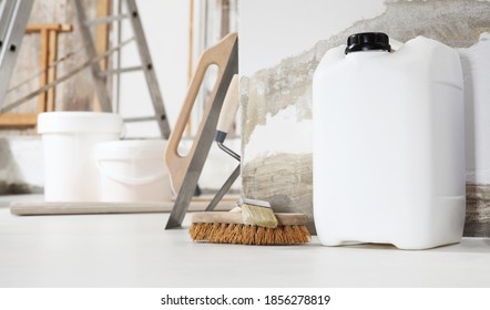 Indoor Shot Close Up Frontal View Of Bricklayer, Plasterer Or House Painter Tools On White Floor With Primer Jerry Can In Home Renovation Site