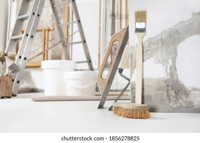 Indoor Shot Close Up Frontal View Of Bricklayer, Plasterer Or House Painter Tools On White Floor With Buckets In Home Renovation Site