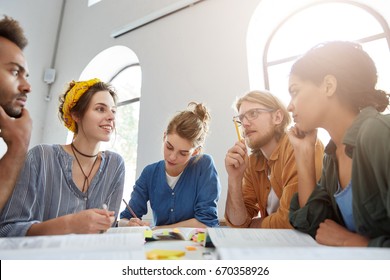 Indoor shot of group of multiracial students having meeting working together using books trying to write article about their studying at university sharing ideas with each other finding suitable words - Shutterstock ID 670358926