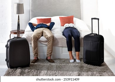 Indoor shot of mature couple lying on bed with luggage 