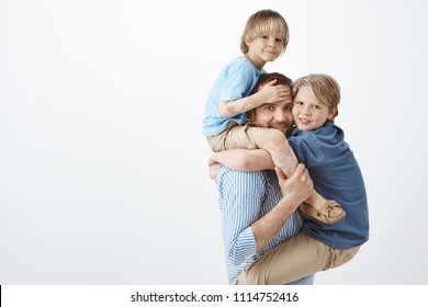 Indoor Shot Of Positive Happy Family Guy Holding Son With Vitiligo On Shoulders And Cute Kid On Chest, Smiling Broadly, Feeling Joyful While Playing With Loving Children, Looking At Mom With Care