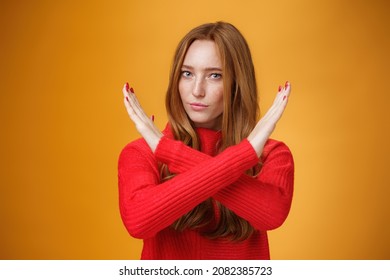 Indoor shot of self-assured attractive powerful woman with red hair and freckles cross arms in no and prohibition gesture forbidding make action standing confident over orange wall - Shutterstock ID 2082385723