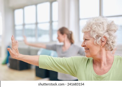 Indoor Shot Of Senior Woman Doing Stretching Exercise At Yoga Class. Women Practicing Yoga At Gym.